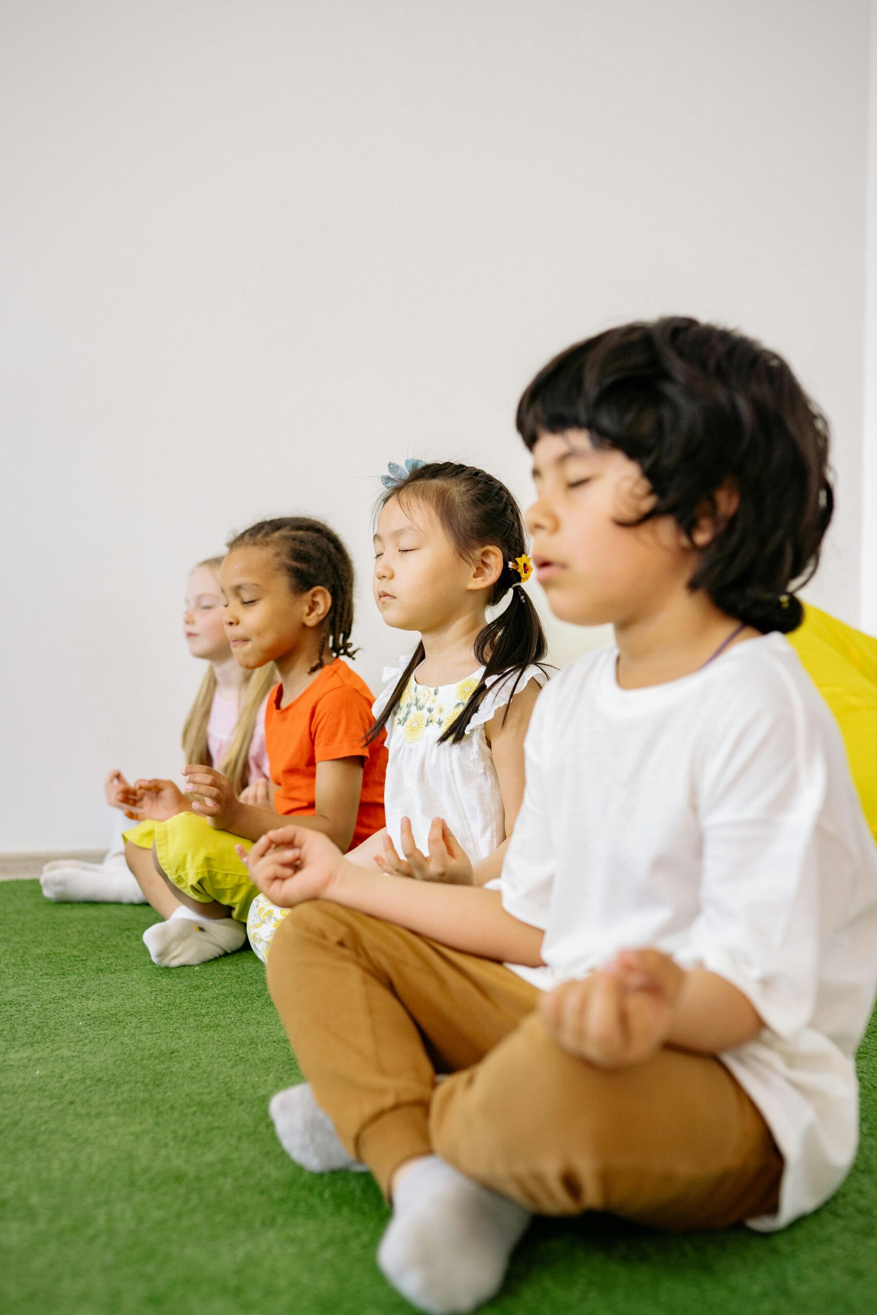 Diverse group of children practicing meditation indoors in a classroom setting.
